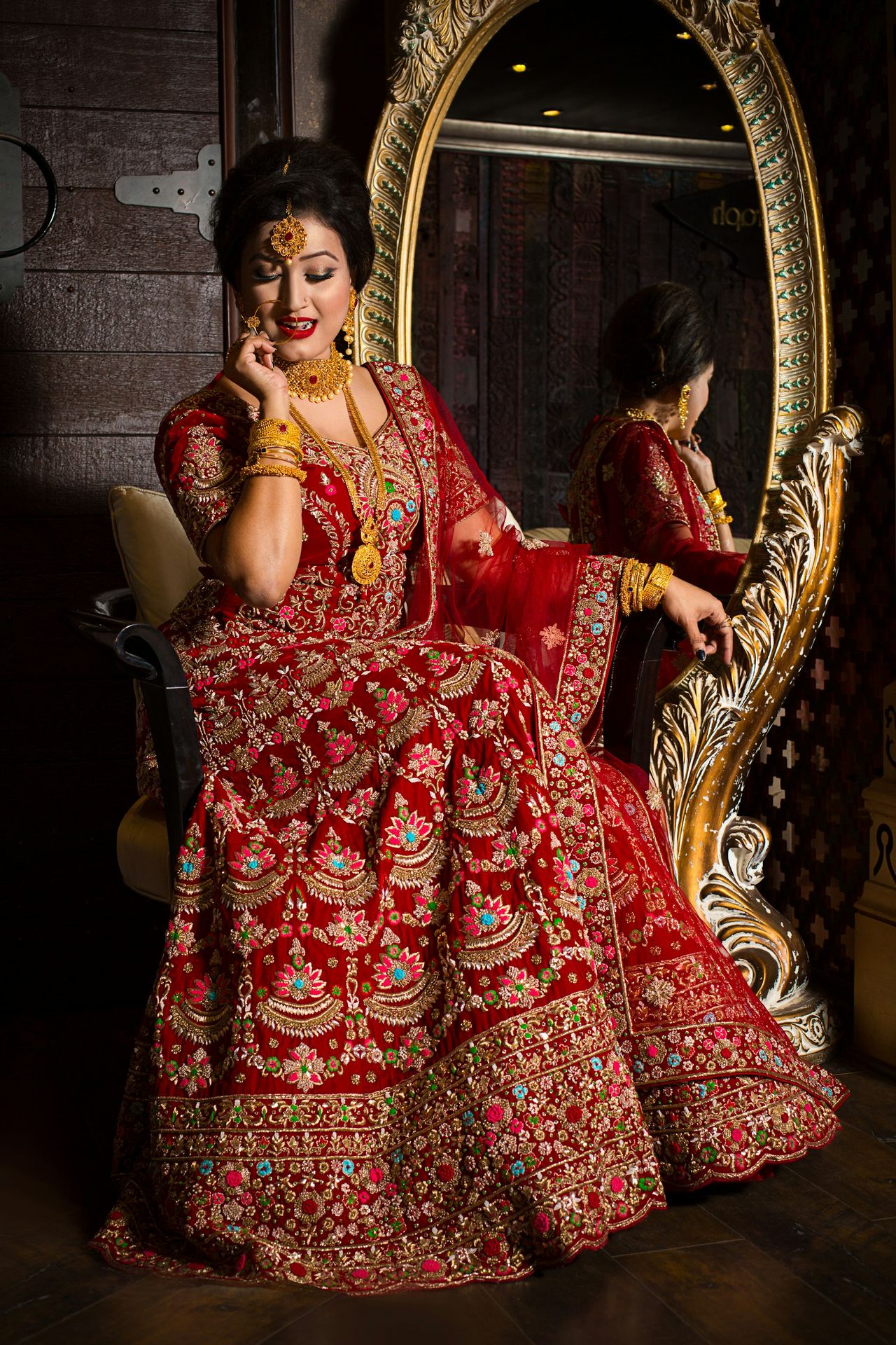 woman in red and gold floral dress sitting on brown wooden armchair